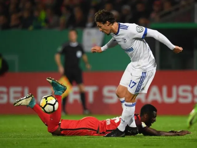 Wiesbadens Stephané Mvibudulu (unten) und der Schalker Benjamin Stambouli beim Zweikampf. Foto: Arne Dedert/dpa