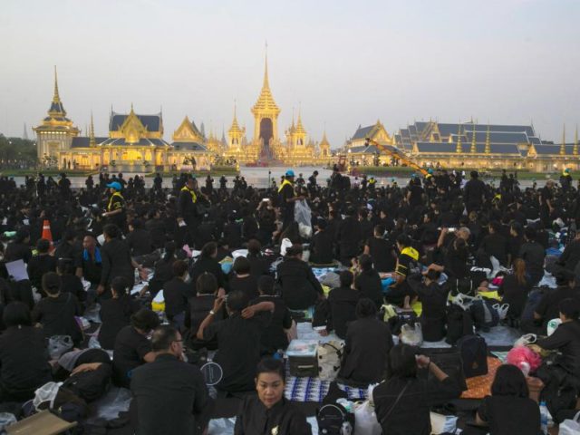 Trauernde Thais sitzenin Bangkok vor dem königlichen Krematorium und dem Bestattungskomplex und warten auf den Beginn der Zeremonie. Foto: Wason Wanichakorn/dpa