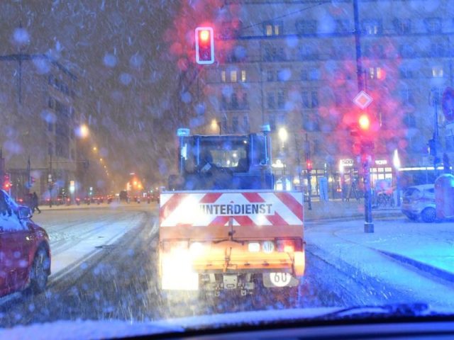 Ein Räumfahrzeug steht in Berlin am Abend im dichten Schneetreiben. Foto: Paul Zinken/dpa