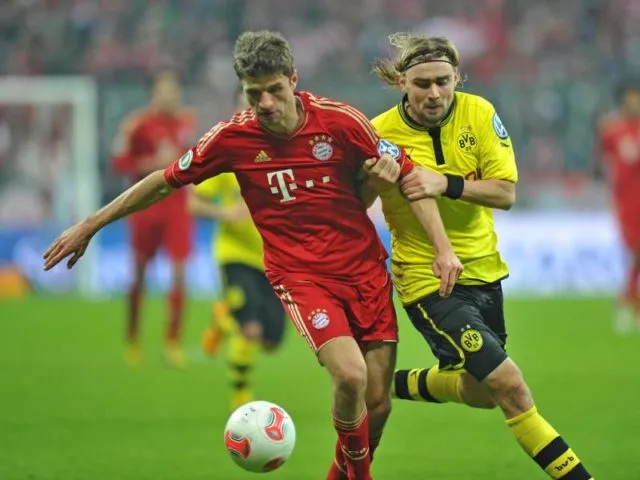 Münchens Thomas Müller (l) im Kampf um den Ball mit BVB-Spieler Marcel Schmelzer. Die Bayern siegen im Viertelfinale mit 1:0. Foto:&nbsp;Marc Müller/dpa