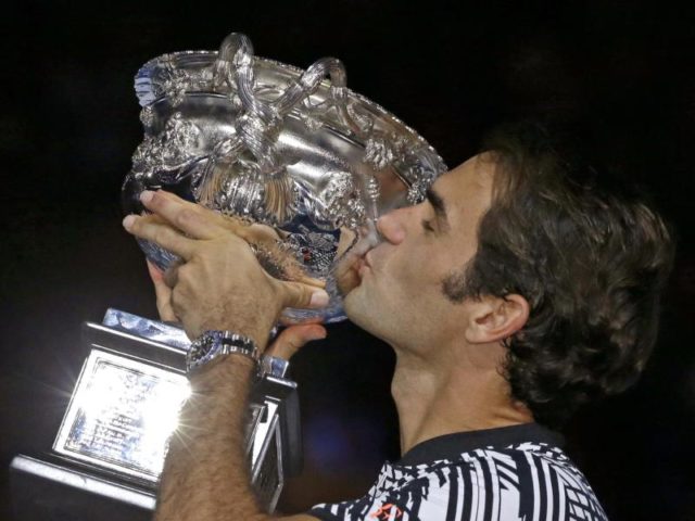 Roger Federer küsst nach seinem Sieg über Rafael Nadal bei den Australian Open den Pokal. Foto: Aaron Favila/dpa