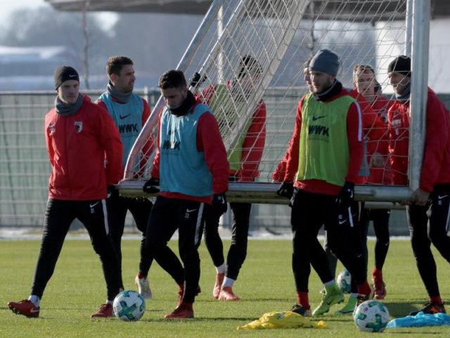 Zum Trainingsauftakt tragen die Spieler des FC Augsburg ein Tor auf den Platz. Foto: Stefan Puchner/dpa