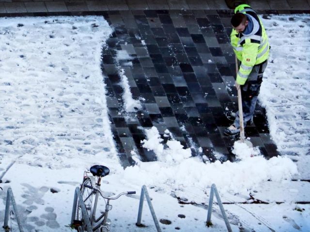 Ein Mann räumt in Düsseldorf Schnee von einem Gehweg. Foto: Martin Gerten/dpa