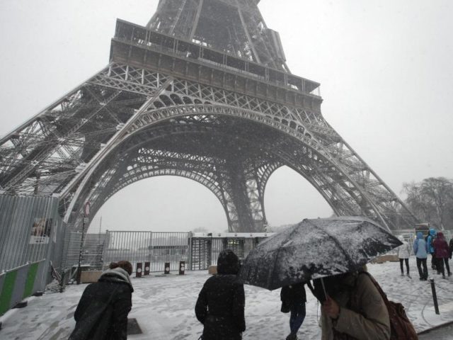 Fußgänger am Eiffelturm. Das Pariser Wahrzeichen bleibt wegen des Winterwettersfür Besucher geschlossen. Foto: Francois Mori/AP/dpa