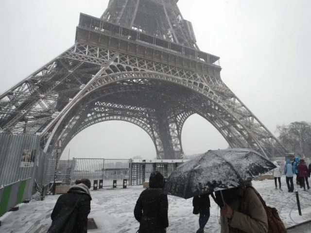 Fußgänger am Eiffelturm. Das Pariser Wahrzeichen bleibt wegen des Winterwettersfür Besucher geschlossen. Foto: Francois Mori/AP/dpa