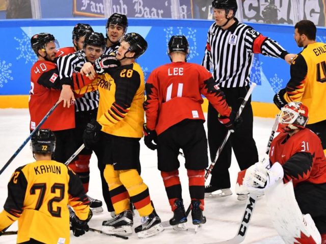 Die Schiedsrichter trennen bei einer Auseinandersetzung die Spieler des kanadischen und deutschen Teams. Foto: Peter Kneffel/dpa