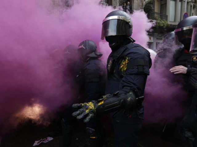 Während der Zusammenstöße mit Demonstranten in Barcelona stehen Polizisten in einer Rauchwolke. Foto: Emilio Morenatti, AP/dpa