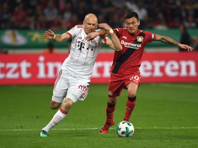 Arm in Arm: Leverkusens Charles Mariano Aranguiz (r) und Bayern-Routinier Arjen Robben beharken sich. Foto: Federico Gambarini/dpa