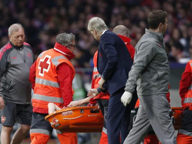 Laurent Koscielny vom FC Arsenal wird verletzt vom Platz getragen. Trainer Arsene Wenger (M) erkundigt sich nach seinem Spieler. Foto: Francisco Seco/AP/dpa