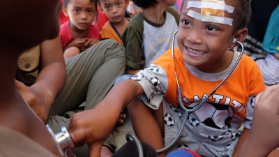 Helfer in indonesischem Katastrophengebiet muntern Kinder mit Hilfsangeboten auf