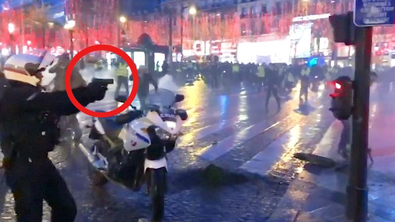 Polizist richtet Waffe auf randalierende Demonstranten auf den Champs Elysees
