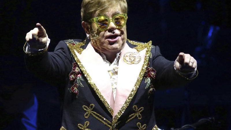 Elton John fährt im Rollstuhl durchs Museum