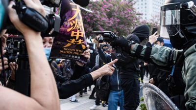 Hongkonger Demonstrantin hält im Angesicht einer Pistole unerschrocken ein Epoch Times-Poster hoch