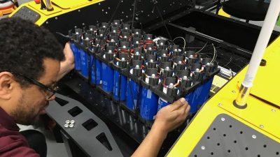 Ein Ingenieur der US-Army installiert eine Batterie im Testfahrzeug mit Stirlingmotor.