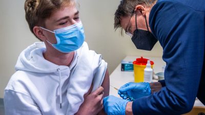 Bundesgesundheitsminister Karl Lauterbach legt bei einem Besuch in einem Impfzentrum in Schwerin selbst Hand an und impft einen Jugendlichen gegen Corona.