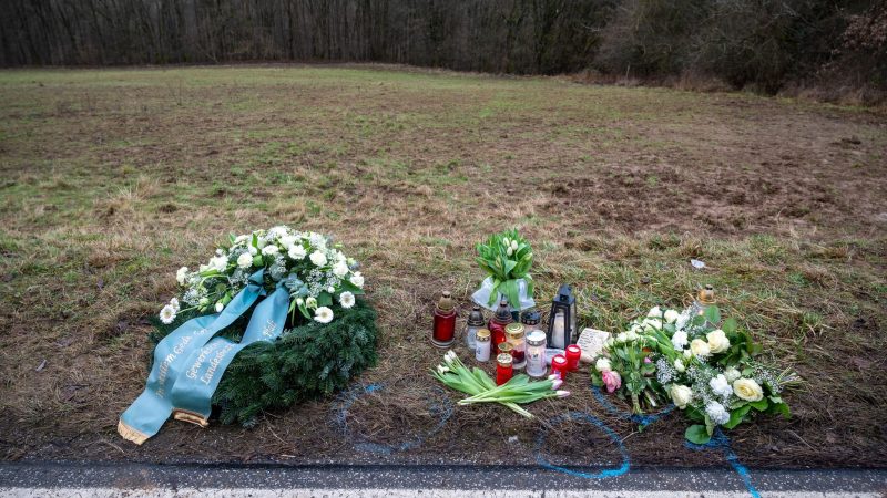 Ein Kranz sowie Blumen und Kerzen liegen am Tatort an der Kreisstraße 22 bei Ulmet (Rheinland-Pfalz).