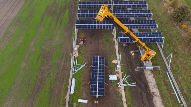 Mit einem Kran wird eine Agrar-Photovoltaik-Anlage in Niedersachsen montiert.