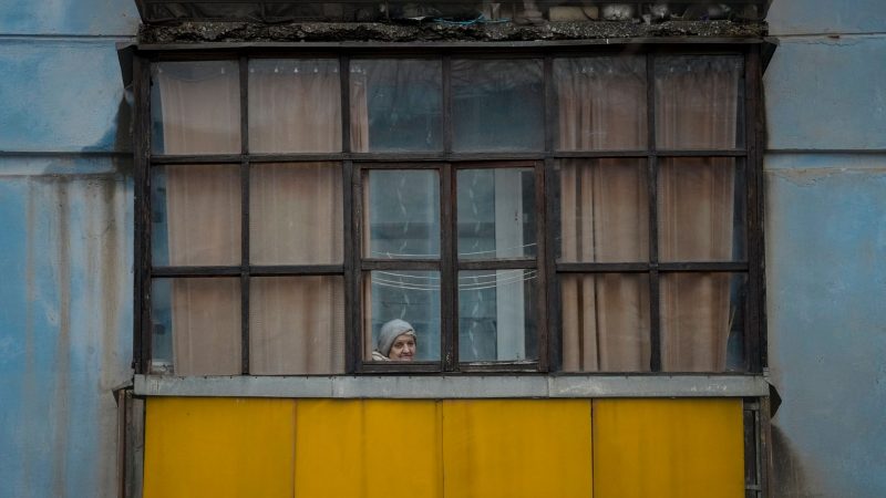 Eine Frau blickt aus dem Fenster eines Hauses in Sjewjerodonezk im Osten der Ukraine.