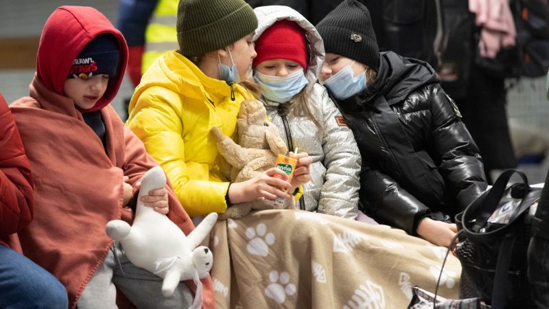 In Decken gehüllt sitzen diese Kinder aus dem ukrainischen Kriegsgebiet auf einer Bank im Berliner Hauptbahnhof.