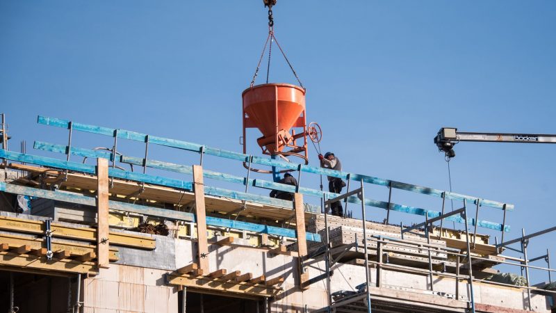 Arbeiter leeren auf einer Baustelle eines Neubaus einen Behälter für Beton.