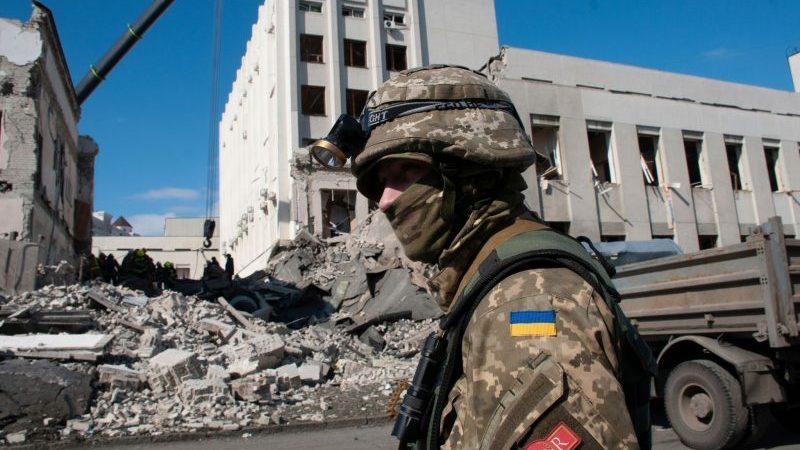 Ein ukrainischer Soldat bewacht ein durch Beschuss beschädigtes Gebäude.