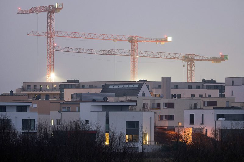 Kräne auf einer Baustelle für Wohnungen stehen hinter Mehrfamilienhäusern des relativ neuen Stadtteils Kalbach-Riedberg in Frankfurt.