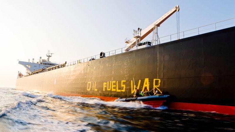 Aktivisten der Umweltorganisation Greenpeace malen in Fehmarn den Schriftzug «Oil fuels war» auf den Rumpf eines Schiffes, das russisches Öl auf der Ostsee transportiert.