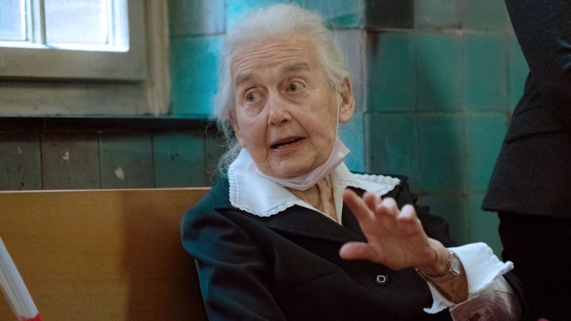 Holocaust-Leugnerin Ursula Haverbeck sitzt auf einer Bank in einem Gerichtsflur. )