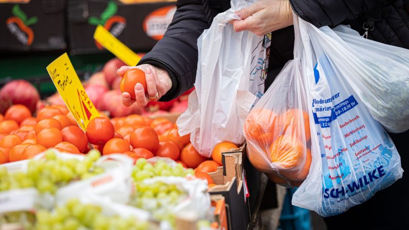 Eine Kundin begutachtet eine Tomate auf einem Wochenmarkt in Hannover. Wegen der steigenden Inflation müssen viele Menschen in Deutschland den Gürtel enger schnallen,