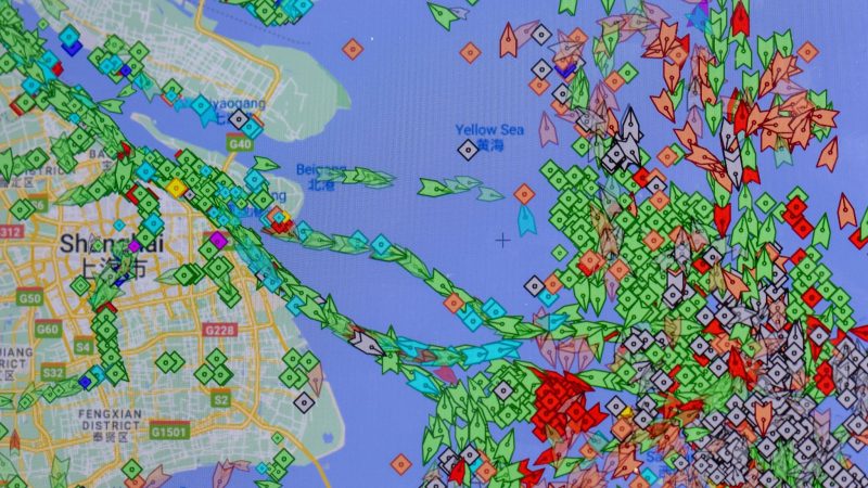 Auf einem Smartphone-Monitor ist die App «MarineTraffic» zu sehen, die die Positionen von Frachtschiffen (grün) vor dem Hafen von Shanghai anzeigt.
