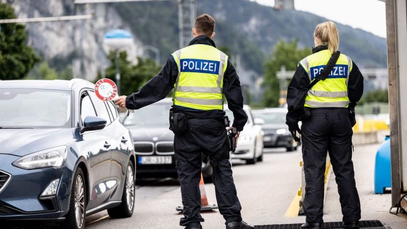 Deutsche Bundespolizisten beobachten an der Grenze zu Österreich auf der Autobahn A93 den Verkehr.