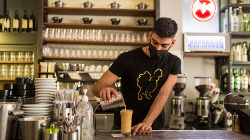 Ein Barista bereitet einen Kaffee in einem Coffee-Shop im Zentrum Athens zu. Laut Tourismusverband konnte die Tourismusbranche zum Saisonstart rund 50.000 Stellen nicht besetzen.