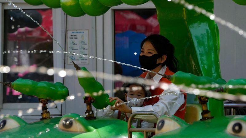 Eine Frau und ein Kind mit Mund-Nasen-Schutz spielen in Peking. Chinas Hauptstadt hat strenge Corona-Restriktionen eingeführt. Die meisten Geschäften und öffentlichen Einrichtungen dürfen nur noch Menschen mit einem aktuellen PCR-Test einlassen.