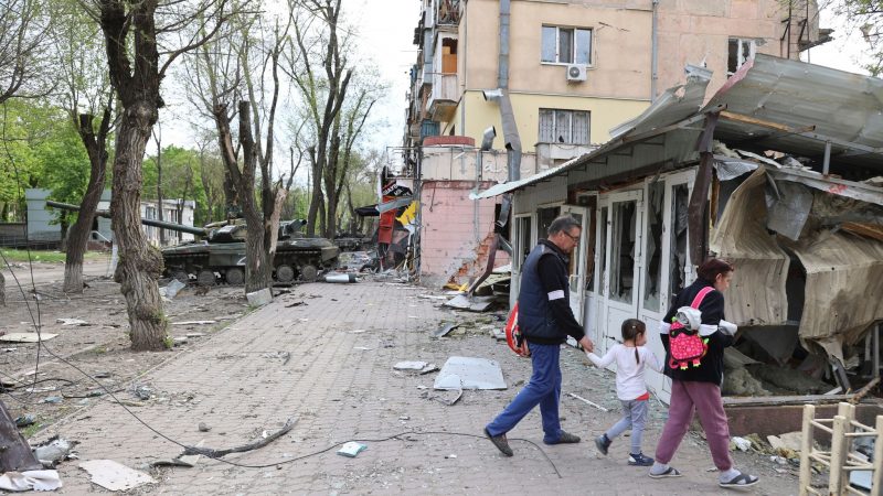 Menschen laufen durch das zerstörte Mariupol.
