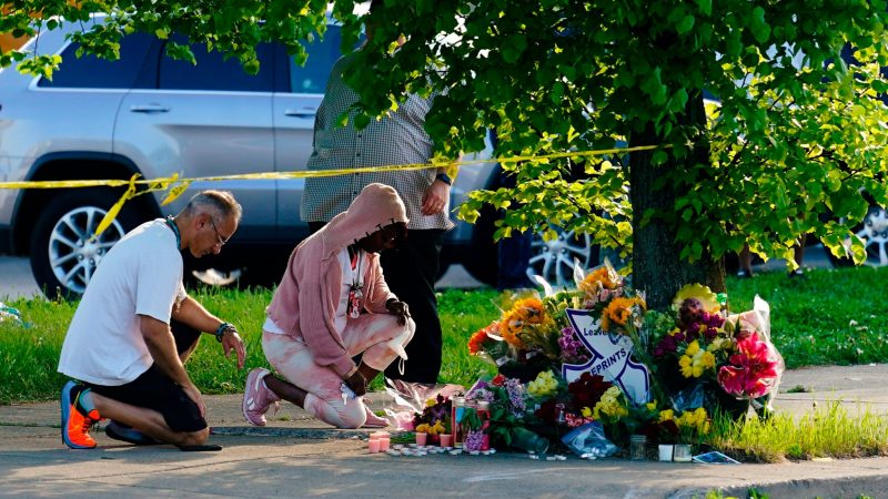 Menschen knien vor Blumen, um den Opfern tödlicher Schüsse in einem Supermarkt in Buffalo die letzte Ehre zu erweisen.