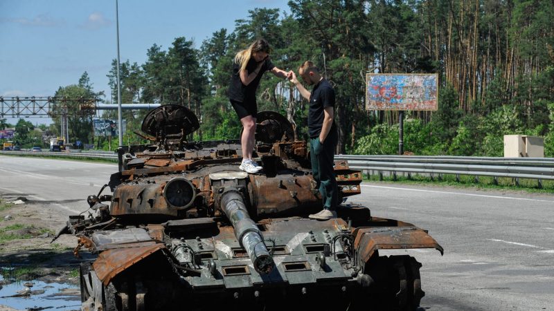 Etwa 40 km westlich von Kiew inspizieren zwei junge Menschen einen zerstörten Panzer der russischen Armee.