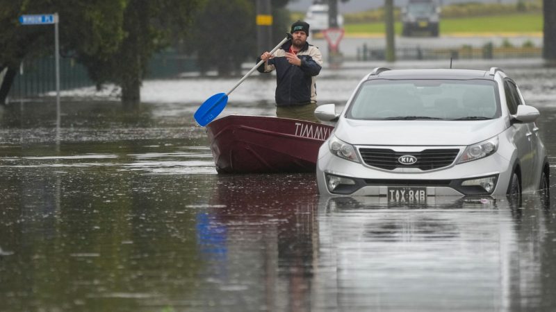 Ein Mann paddelt mit seinem Boot auf einer überfluteten Straße am Stadtrand von Sydney.