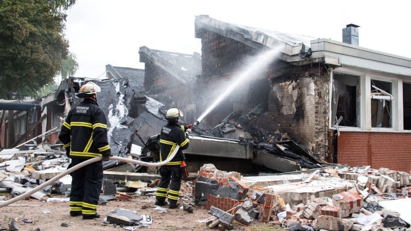 Feuerwehrleute löschen Trümmer eines Gebäudes der Stadtteilschule Finkenwerder.