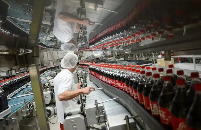 Ein Mitarbeiter steht an einem Transportband mit Getränkeflaschen an den Abfüllanlagen der Coca-Cola Erfrischungsgetränke AG.
