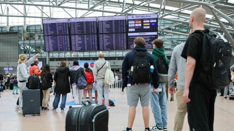 Flugreisende stehen unter den Anzeigetafeln und vor den Check-in-Schaltern am Airport Hamburg.