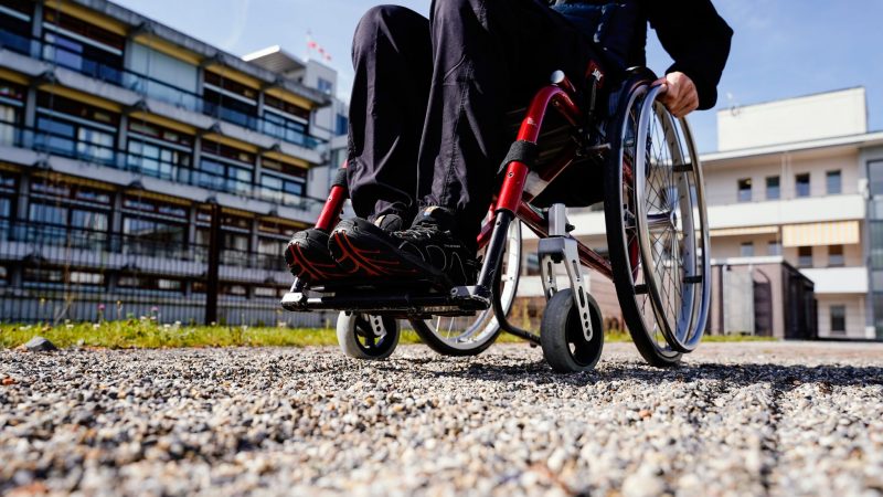 Nicht gerade optimal - ein Rollstuhlfahrer fährt über einen Kiesweg.