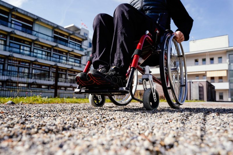 Nicht gerade optimal - ein Rollstuhlfahrer fährt über einen Kiesweg.
