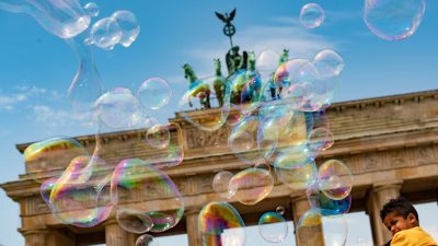 Ein Straßenkünstler zeichnet übergroße Seifenblasen in den Himmel vor dem Brandenburger Tor in Berlin.
