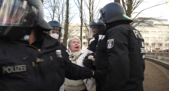 Eine ältere Dame wird zur Feststellung ihrer Personalien bei einer Corona-Demo von der Polizei abgeführt.