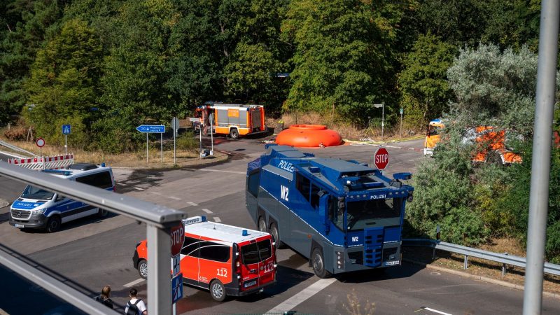 Feuerwehrautos und Fahrzeuge der Polizei stehen in der Nähe der Brandstelle im Grunewald.