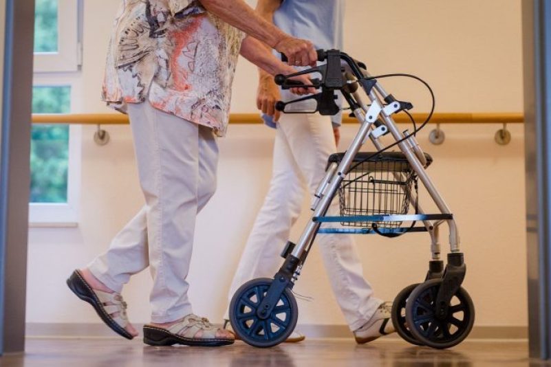 Eine Pflegekraft geht in einem Stuttgarter Pflegeheim mit einer älteren Frau über den Flur.