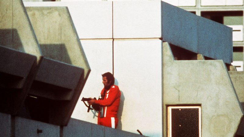 Ein bewaffneter Polizeibeamter im Trainingsanzug sichert am 05.09.1972 im Olympischen Dorf in München den Block, wo Terroristen die israelischen Geiseln festhalten.