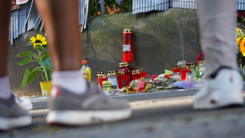 Menschen stehen in Dortmund vor einem Zaun, an dem mit Kerzen und Blumen des von der Polizei erschossenen Jugendlichen gedacht wird.