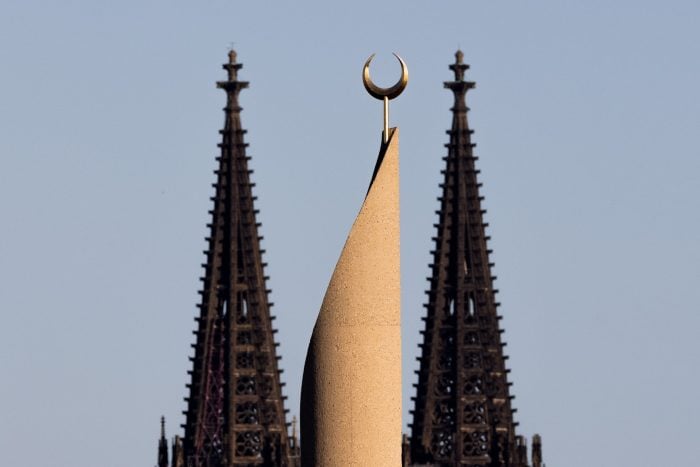 Der Kölner Dom und ein Minarett der Zentralmoschee der DITIB (Türkisch-Islamische Union der Anstalt für Religion) sind im Licht der untergehenden Sonne zu sehen.