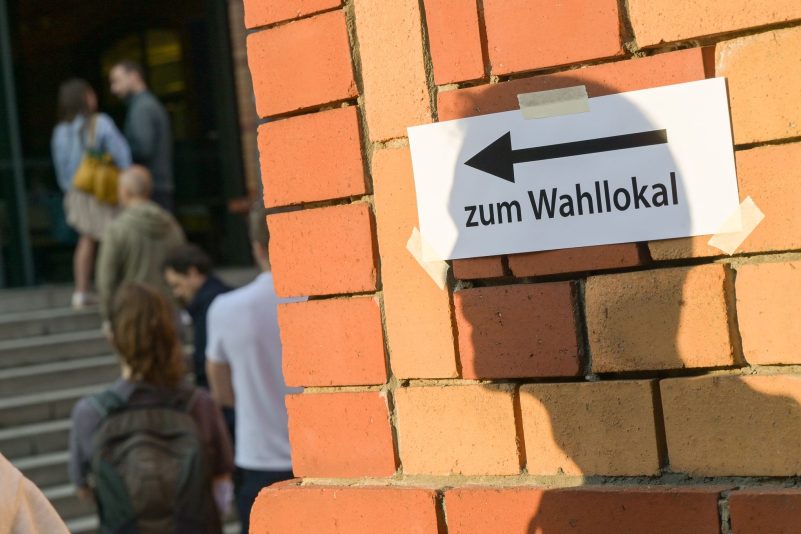 Wählerinnen und Wähler stehen kurz vor der Schließung der Wahllokale vor einem Wahllokal in Berlin.